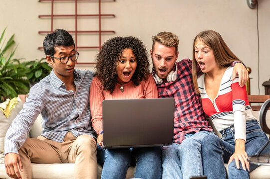 Multiethnic gen z friends react with surprise while watching unexpected content together on a laptop. Group expressions convey shock, suspense, viral media, and shared excitement.