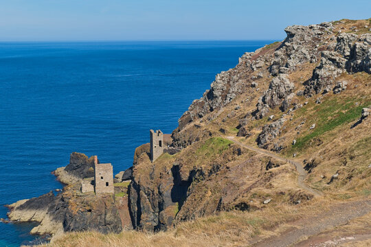 A scenic view of two historic mine engine houses perched on rugged Cornish cliffs overlooking a vibrant blue sea - Botallack Mine & Engine House, Cornwall, UK