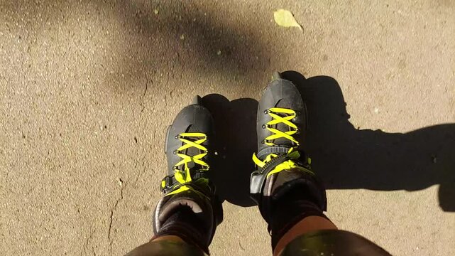 POV close up of feet in roller skates riding on asphalt path in park