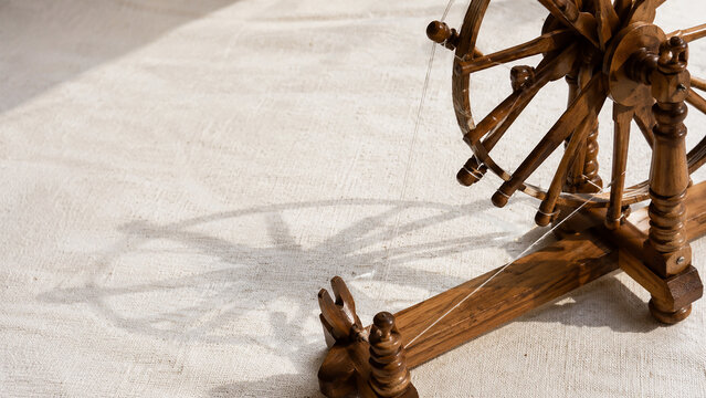 Vintage wooden spinning wheel casting a beautiful artistic shadow on a clean white floor background