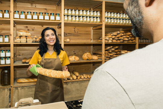 Bakery shop employee selling fresh bread to customer