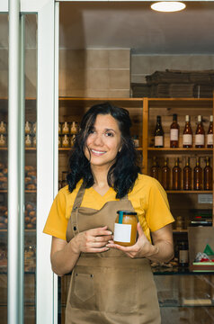 Woman shop owner presenting a jar of natural honey