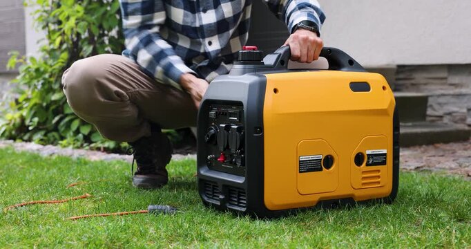 Man starting portable inverter generator for home backup power or outdoor electricity supply