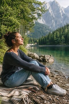 Digital Detox in den Bergen: Frau sitzt am klaren Bergsee und genie&szlig;t mit geschlossenen Augen die Ruhe der Natur &ndash; bewusste Auszeit, Achtsamkeit und Erholung im Freien.