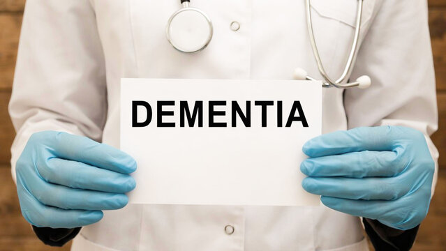 Doctor in gloved hands holding paper card with Dementia text message