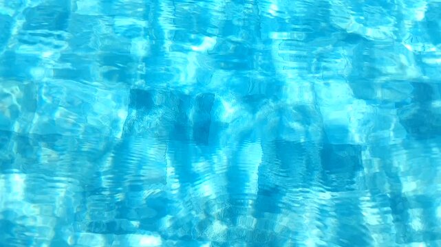 Bright turquoise swimming pool water surface with sun rays and caustics background