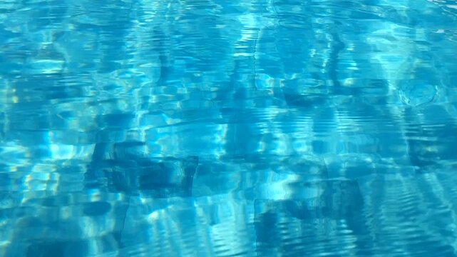 Clear blue swimming pool water ripples with tiled bottom background