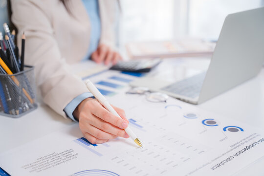 Financial Analysis in Action: A professional meticulously analyzes financial reports and charts, with a laptop and calculator nearby, indicating a focused effort in accounting or business strategy.