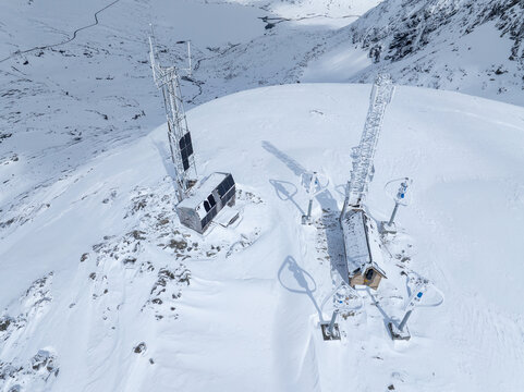 Aerial view of communication towers and a small weather station on a snow-covered mountain peak in Andalsnes, More og Romsdal, Norway.