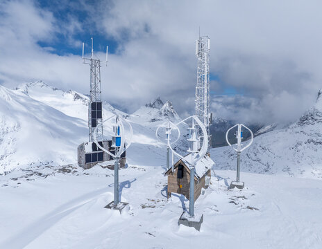 Aerial view of vertical axis wind turbines and communication towers on a snow-covered mountain peak in Andalsnes, More og Romsdal, Norway.