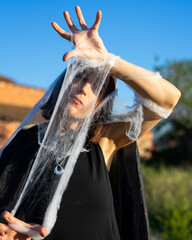 Naklejka premium Woman Posing with Spooky Spider Web Material Outdoors