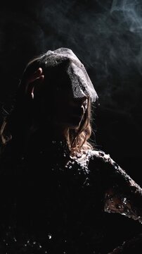 Mysterious woman in sparkling rhinestone veil surrounded by smoke