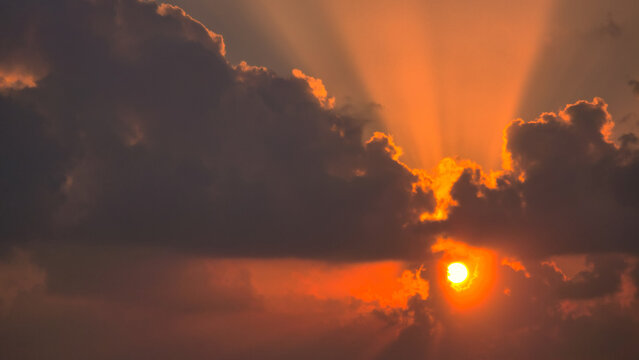 Dramatic sunset with sun rays breaking through dark clouds