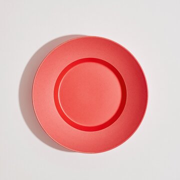 Red handmade ceramic bowl with a speckled matte finish, centered on a clean white background with copy space for food styling and product mockups
