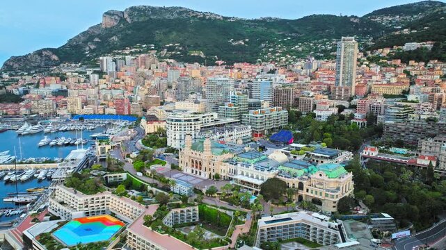 Aerial view of Monaco and Monte Carlo. Elegant buildings, green gardens, harbour waters and hillside cityscape create a luxurious Mediterranean destination.