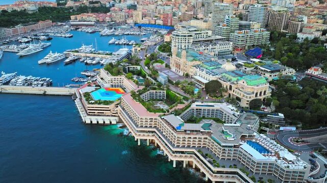 Drone view of Port Hercules in Monaco. Marina docks, luxury yachts, waterfront buildings and the surrounding city create an iconic Riviera harbour scene.