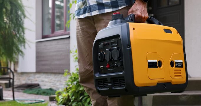 Man carrying portable gasoline generator for emergency home power supply