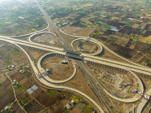 Aerial view of the Sinnar Interchange featuring a complex cloverleaf highway junction surrounded by vast agricultural fields and dry rural landscape in Sinnar, Maharashtra, India.