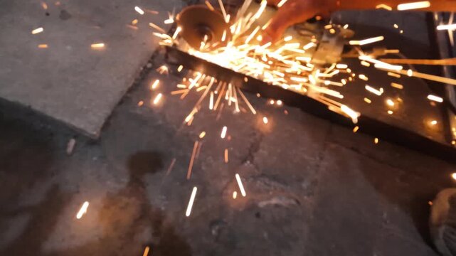 Worker sparks metal grinding.