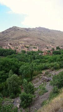 Marrakech, morocco. August 9, 2026. Scenic landscape of a traditional moroccan village nestled in a lush green valley at the foot of the majestic atlas mountains near marrakech