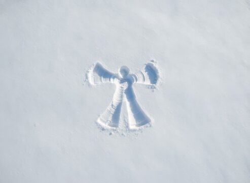 Snow angel imprinted in fresh white snow during winter