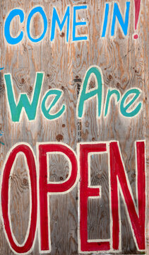 we're open sign-A hand-painted wooden sign with colorful lettering reads "COME IN! We Are OPEN."