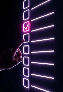 Hand selecting checkbox on neon-lit task board  