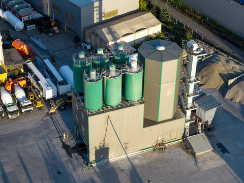 Aerial view of a concrete plant with green silos, industrial structures, and construction vehicles in Poland.