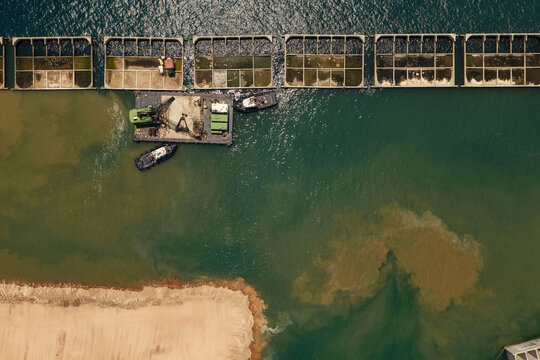 Aerial view of industrial floating pens and a crane barge operating in the port waters of Piraeus, Greece.