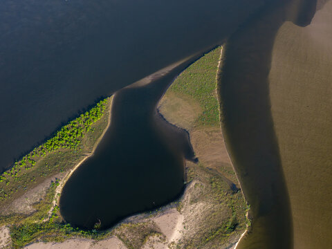 Aerial view of a river with low water levels exposing sandy banks and lush green vegetation in Poland.