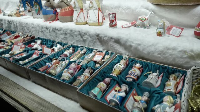 Rows of painted figurine ornaments including dolls, angels, soldiers, snowmen, and animal shapes arranged in multiple rectangular trays lined with teal velvet, each ornament tagged with price or