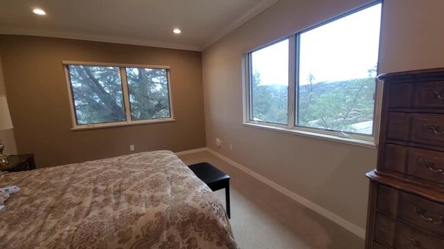 Cozy bedroom interior with beige walls, floral bedding, tufted headboard, and big windows view porch