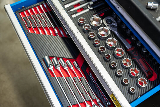 Organized tool drawer displays socket set, ratchet handles, and screwdriver assortment in fitted foam inserts. Bright red lining and metal finish 