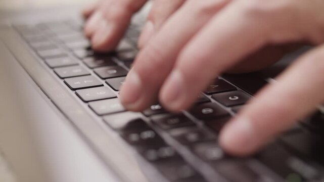 Close up macro of hands typing on laptop keyboard computer