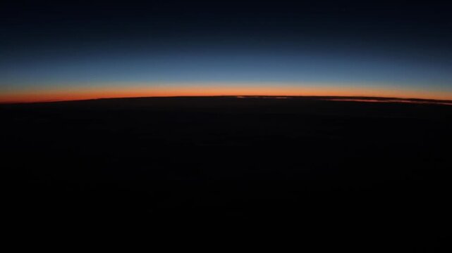 Pilot&rsquo;s point of view of a colorful sunrise over the North Atlantic Ocean from cruising altitude, with a glowing horizon and expansive cloud layers below.
