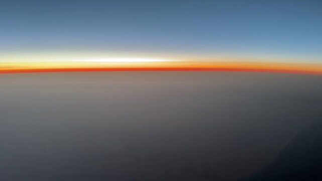 Pilot&rsquo;s point of view of a colorful sunrise over the North Atlantic Ocean from cruising altitude, with a glowing horizon and expansive cloud layers below.
