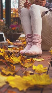 Cozy autumn morning on a wooden terrace with warm socks, blanket, and coffee. Peaceful fall mood, golden leaves, soft light, sweater weather lifestyle and comfort in nature.