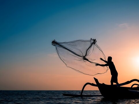 Silhouette of fisherman throwing cast net from boat at sunset