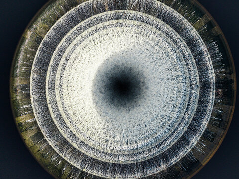 Aerial view of the circular spillway of Ladybower Reservoir in the Peak District National Park, showing concentric concrete rings and water flowing into the central drain, England, United Kingdom.