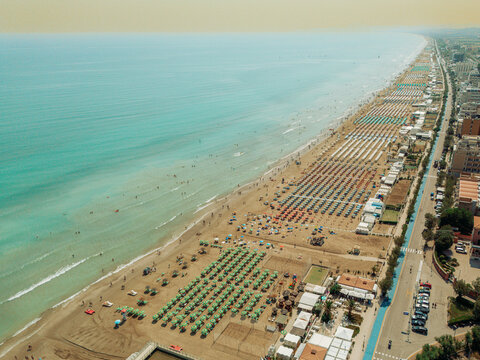 Aerial view of the sandy beach in Senigallia, featuring rows of colorful umbrellas and sun loungers along the Adriatic Sea coastline in Senigallia, Marche, Italy.