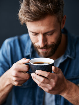 Close up portrait of a young man enjoying the aroma of a hot cup of espresso coffee.