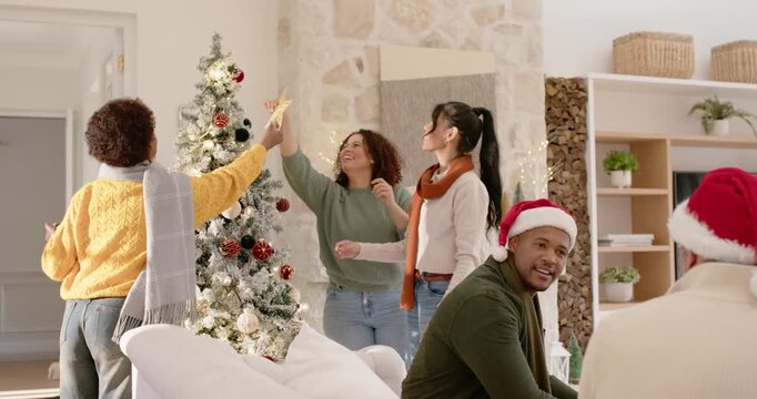 Diverse family and friends decorating Xmas tree at home, passing star topper while woman placing it