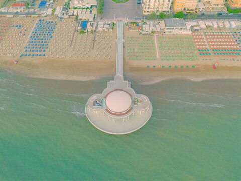 Aerial view of the Rotonda a Mare extending into the Adriatic Sea with rows of colorful beach umbrellas on the sandy shore in Senigallia, Marche, Italy.