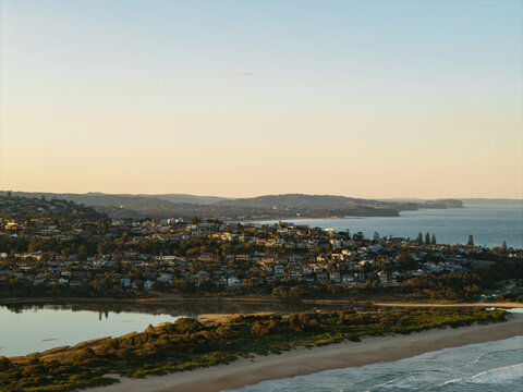 Aerial view of the coastal suburb of Dee Why featuring a sandy beach, a lagoon, and residential houses on the hillside overlooking the Pacific Ocean in Dee Why, New South Wales, Australia.