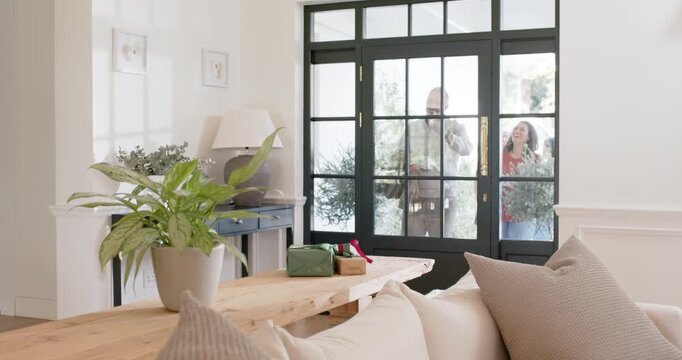 African American woman seeing visitors pausing at front door, opening, taking cup, welcoming guests