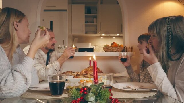 Family celebrating christmas or thanksgiving day dinner together at home with candles, food, and drinks, enjoying a festive holiday meal in a cozy and warm setting
