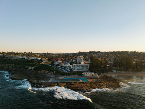 Aerial view of the Dee Why Rock Pool with crashing waves and residential buildings in the background Dee Why, New South Wales, Australia.