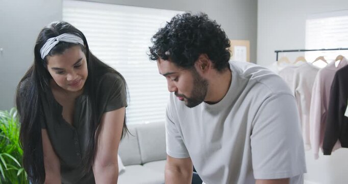 African American couple leaning over tabletop at home, man pointing to plan, woman studying