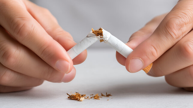 Close-up of hands breaking a cigarette in half, symbolizing smoking cessation, quitting tobacco, addiction recovery and a decision to adopt a healthier lifestyle.