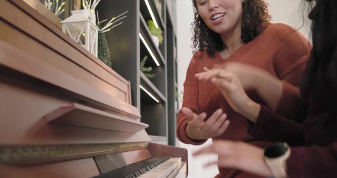 African American women practicing piano duet at home, Santa hat woman leading hands sharing holiday